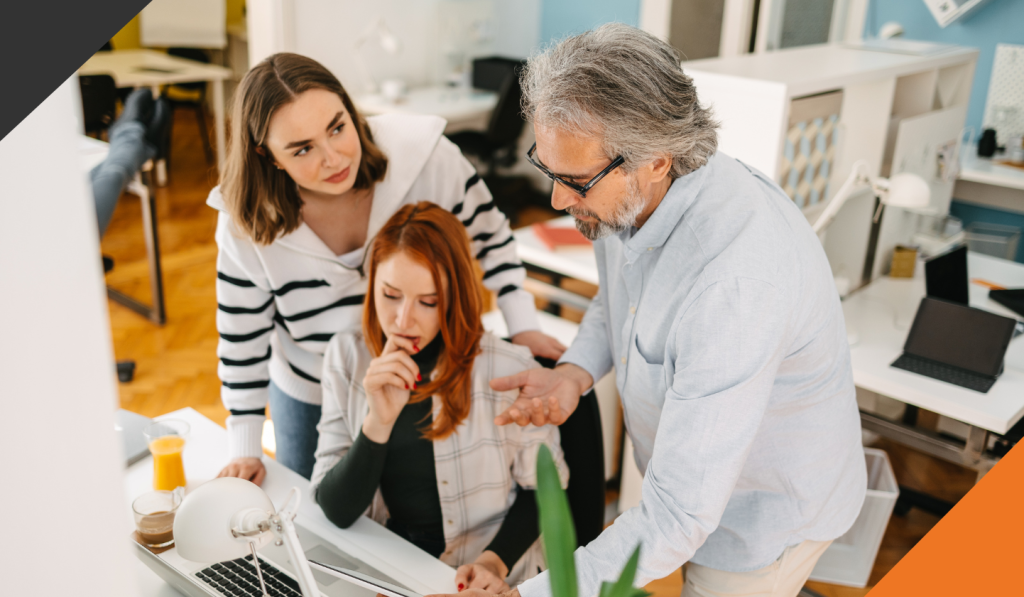 2 women and one man gathered around a desk discussing how to harness the power of delegation for high-performing teams.