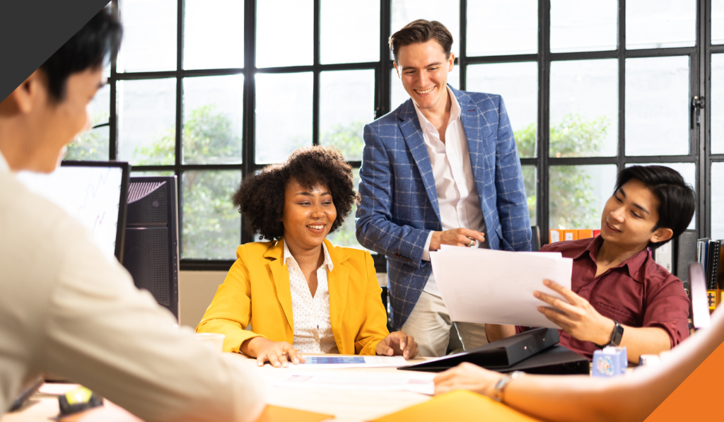 4 employees seated around a meeting table reviewing self awareness as leaders