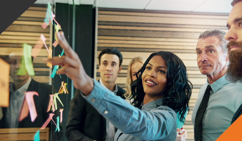 a group of five employees standing at a board mapping how to develop high performing teams