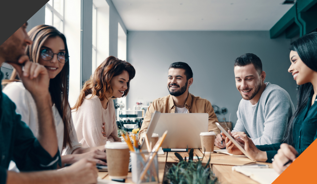 five employees in a meeting room at a desk executing successful training and development strategies
