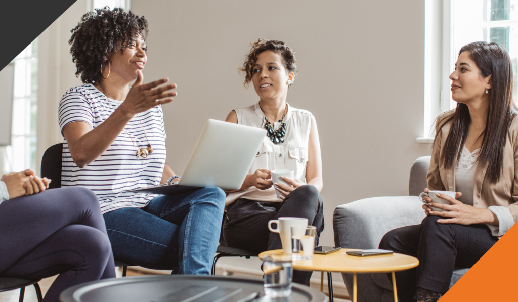four female employees seated in a meeting room addressing how to ignite team performance with regular feedback