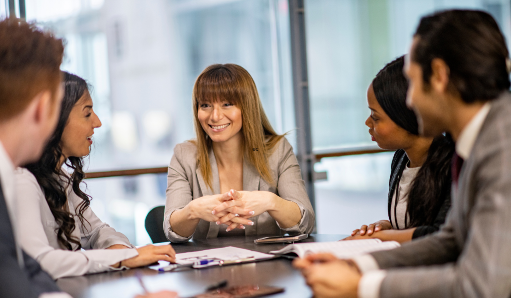woman seated at the head of a meeting table demonstrating How to Be a bold and resilient leader