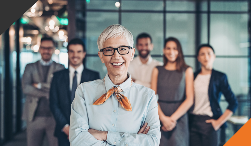 A team leader stands in front of her five employees demonstrating characteristics of a Fierce leader 