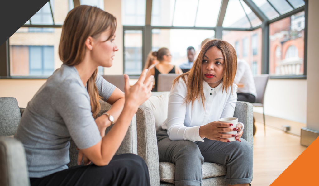 two female employees seated in chairs who are learning how to be comfortable with confrontation