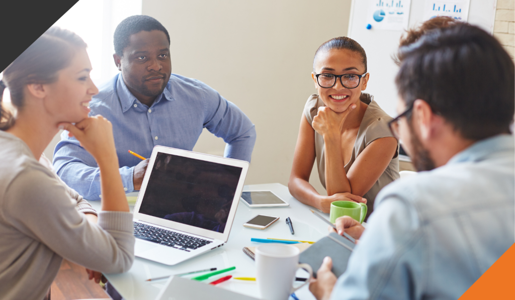 four employees seated at a meeting table having an effective meeting with planned agenda