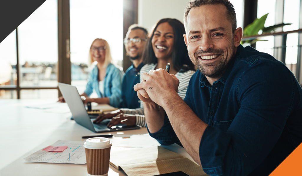 employees seated at a table smiling after learning the top 3 tips to reduce employee stress at work and taking initiatives to alleviate stress